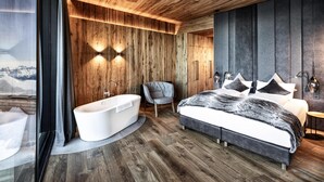 A modern bedroom with a large bed, a bathtub, and a chair. - Apartment in Kaltenbach With Ski-in/ski-out (Kaltenbach)