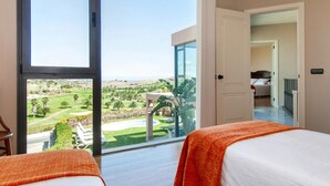 Ein Hotelzimmer mit einer großen Schiebetür, die zu einem privaten Außenbereich mit Blick auf einen Golfplatz und Grünflächen führt.