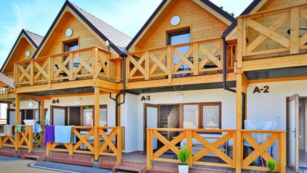 Una fila de cabañas de madera con balcones, numeradas A-2, A-3 y A-4, con un diseño sencillo y rústico.