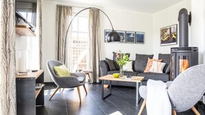 Een moderne woonkamer met een bank, fauteuils, een salontafel en een open haard.