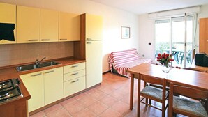 Cocina compacta con estufa a gas, pileta y alacenas de madera. Cuenta con un comedor con mesa y sillas, además de un espacio exterior cubierto con asientos.