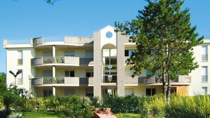 Un hotel de varios pisos con balcones, un atrio central y un jardín ajardinado.