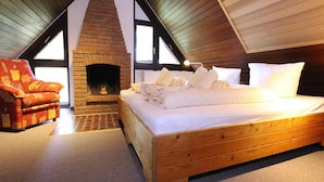 A bedroom with a wooden bed, a brick fireplace, and a red armchair. - Appartement in Westerland auf Sylt (Sylt)