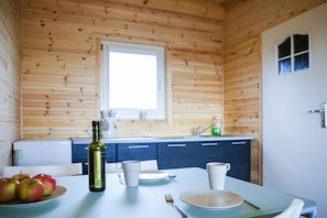 A wooden cabin interior with a dining table set for two, a bottle of wine, and apples on the table. - Holiday House in Rewal Near Baltic Beach (Rewal)