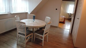 A dining area with a round table and four chairs, a radiator, and a window with curtains. - Cottage in Stepnica Near Szczecin Lagoon (Stepnica)