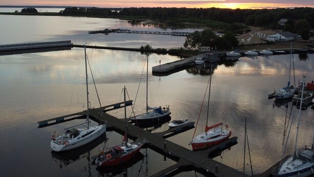 A marina with several boats docked, a pier extending into the water, and a sunset in the background. - Cottage in Stepnica Near Szczecin Lagoon (Stepnica)
