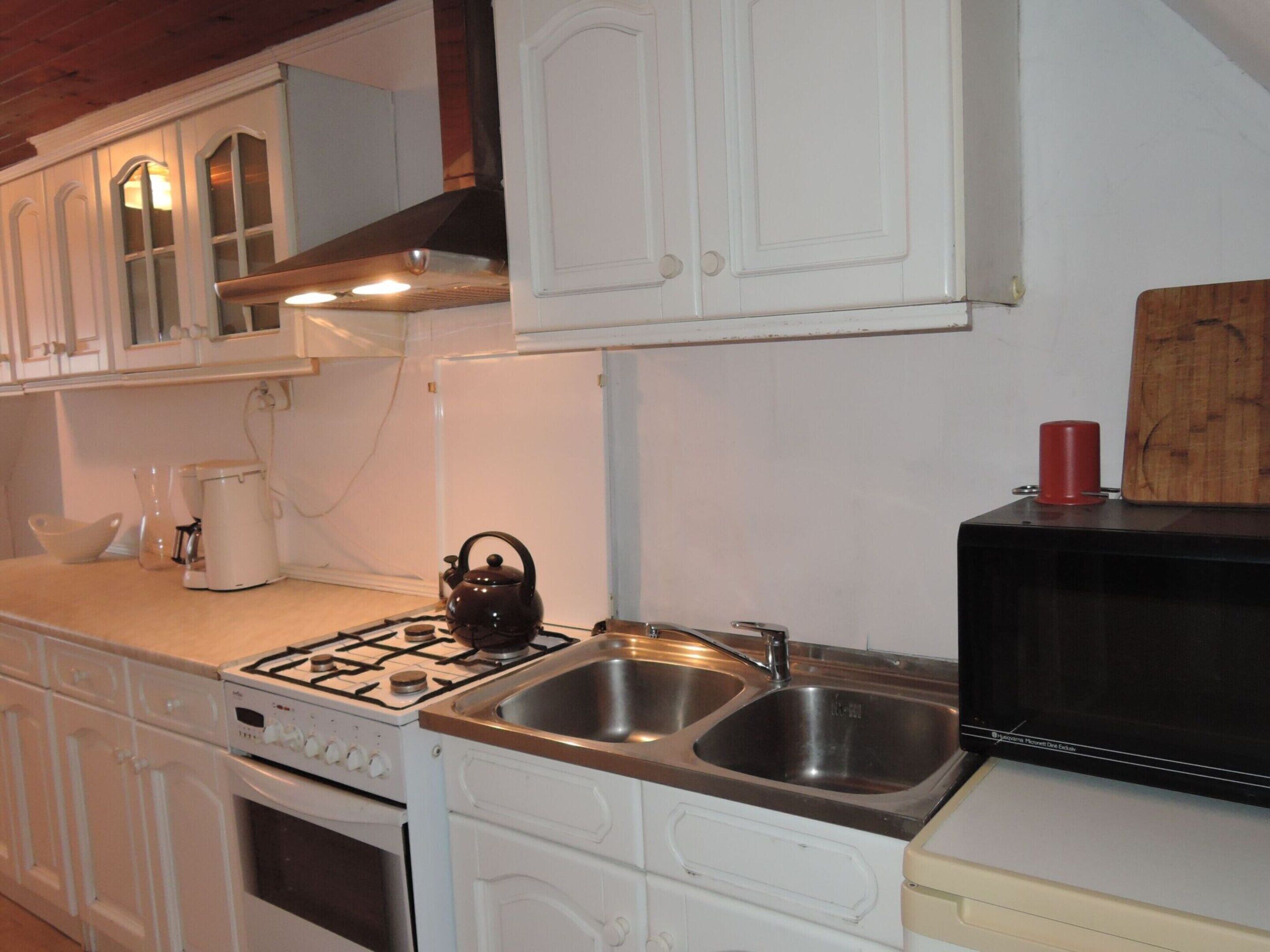 A kitchen with white cabinetry, a gas stove, a sink, and a microwave.