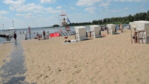 A beach with beach chairs, a lifeguard tower, and a pier in the background. - Cottage in Stepnica Near Szczecin Lagoon (Stepnica)