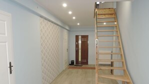 A hallway with a wooden ladder, light blue walls, and a patterned wallpaper on one side. - Cottage in Stepnica Near Szczecin Lagoon (Stepnica)