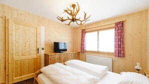 Una stanza in legno con un letto, una televisione e una finestra con tende.
