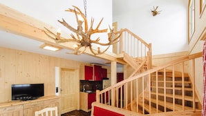 Un interno in legno con zona pranzo, televisione, scale e cucina.