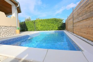 A swimming pool with a stone wall and wooden fence, surrounded by a clear sky. - Apartment in Kakma Near Biograd Beaches (Polaca)