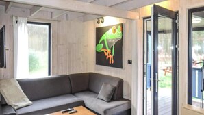 A modern living room with a grey sofa, a wooden coffee table, and a large window. - Holiday Home, Nowe Warpno for 6 Persons (Nowe Warpno)