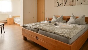 Ein Schlafzimmer mit einem hölzernen Bett, einem Nachttisch, einem Stuhl und einem Fenster mit Vorhängen.