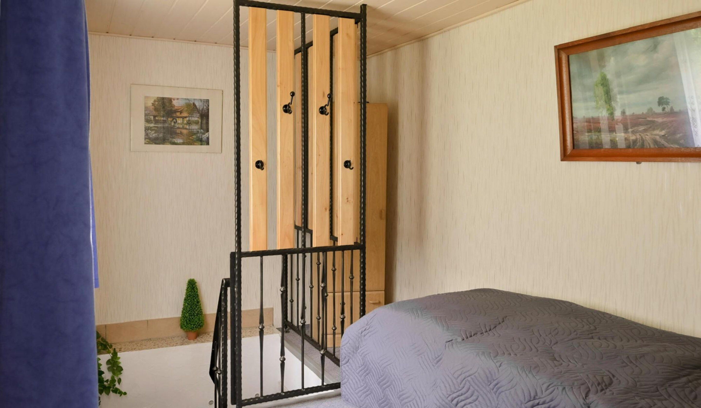 Une chambre à coucher avec un lit, une fenêtre, une porte et une petite plante.