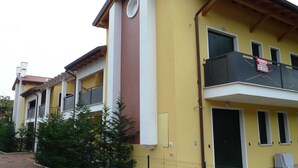 A yellow building with a balcony, a door, and a window. - Villa Faro Vecchio in Cavallino-treporti-formerly TUI Ferienhaus (Cavallino-Treporti)