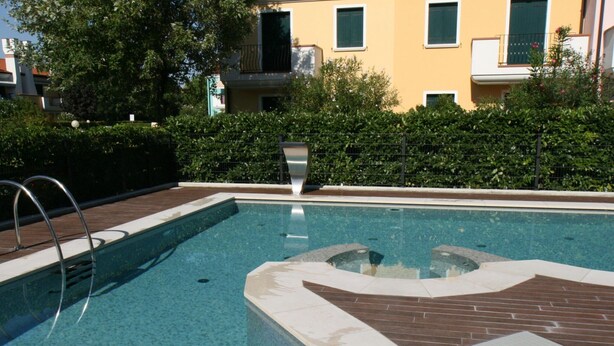 A rectangular swimming pool with a metal ladder on the left, surrounded by a brick deck. - Villa Faro Vecchio in Cavallino-treporti-formerly TUI Ferienhaus (Cavallino-Treporti)