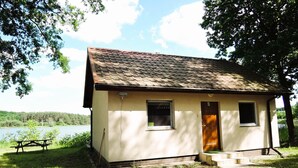 A small, single-story cabin with a tiled roof, a front door, and a window. - Cottage in Szczecin by Puszcza Bukowa Park (Szczecin)