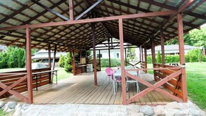 A covered outdoor area with a wooden deck, stone walls, and metal beams. - Cottage in Szczecin by Puszcza Bukowa Park (Szczecin)
