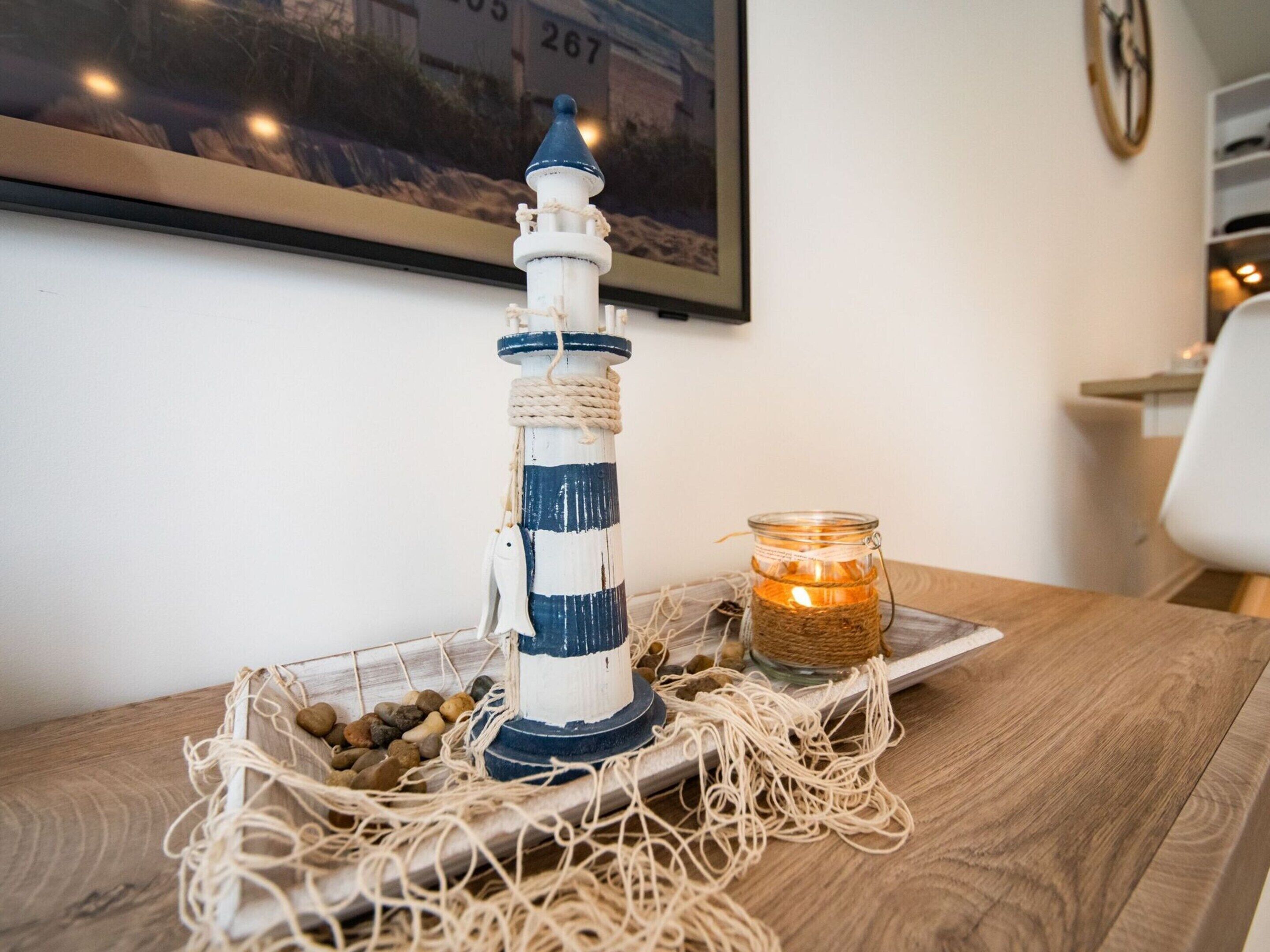 Une pièce maîtresse sur le thème de la marine, comprenant une maquette de phare, une bougie et des éléments décoratifs, le tout disposé sur une table en bois.