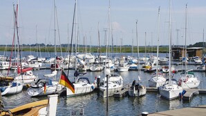 A marina with numerous boats docked, a flag on one boat, and a clear sky. - Thatched Holiday Home in Freest With Terrace (Kröslin)