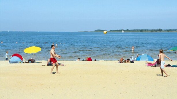 A beach with tents, people, and a volleyball game. - Thatched Holiday Home in Freest With Terrace (Kröslin)