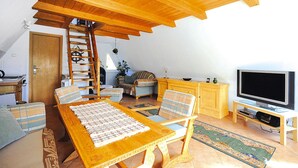 A cozy living room with a wooden table, chairs, a TV, and a ladder. - Thatched Holiday Home in Freest With Terrace (Kröslin)