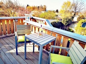 A deck with a table and chairs, surrounded by a wooden fence and trees. - Huebsche Ferienwohnung in Lubmin mit Blick auf Ruegen (Lubmin)