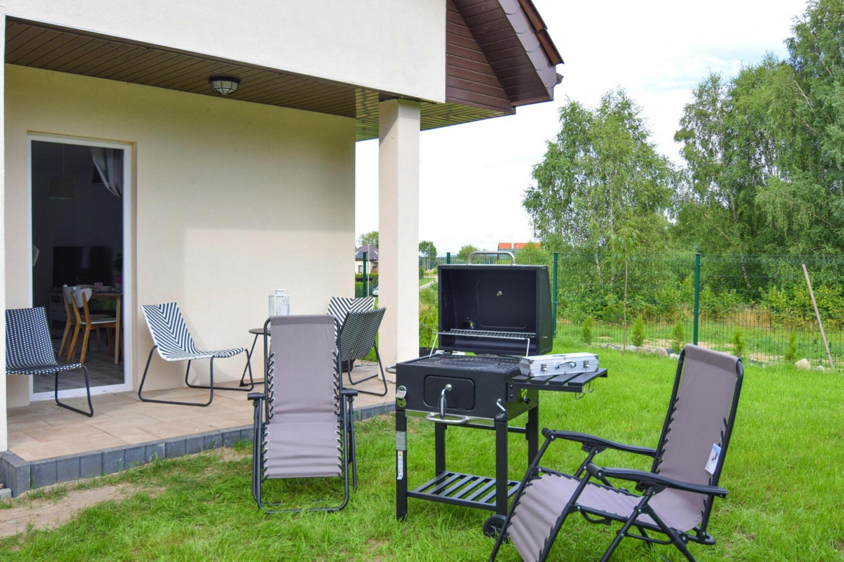 Une terrasse extérieure avec un barbecue, des chaises et une table.
