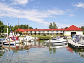 Een jachthaven met aangemeerde boten, een gebouw met een rood dak en een heldere lucht.