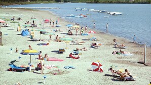 A beach with numerous umbrellas and sun loungers, boats in the water, and a clear view of the sea. - Holiday Flat in the Belvedere Holiday Complex in Grado (Aquileia)