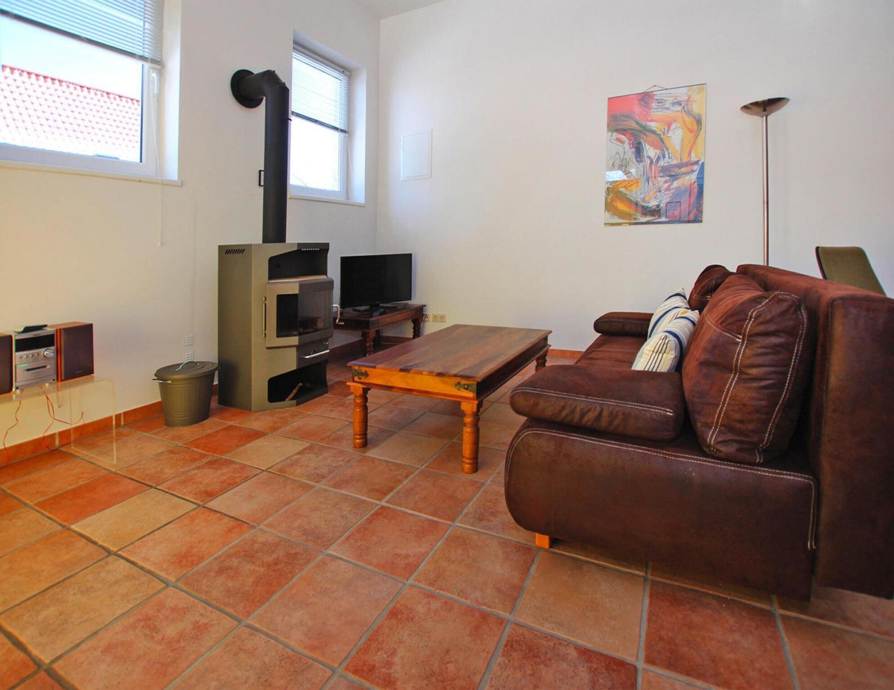 A living room with a brown leather sofa, a wooden coffee table, a TV, and a fireplace.