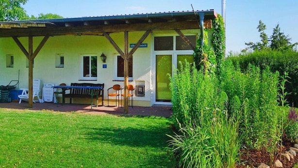 Un edificio con un patio coperto, arredi da esterno e un giardino.