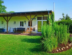 A building with a covered patio area, outdoor seating, and a garden. - Doppelhaushalfte am Flacher See, Klocksin (Klocksin)