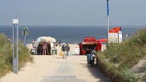 En strandpromenad som leder till små försäljningsstånd vid stranden, med fri utsikt över havet.