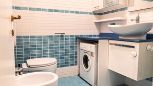 Ein kleines Badezimmer mit Toilette, Waschmaschine und Waschbecken.