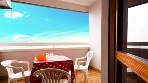 Ein Balkon mit Tisch und Stühlen, Blick zum Himmel und ein Fenster.