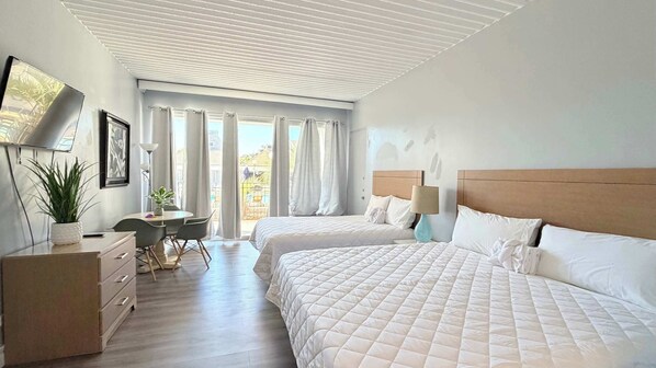 Een hotelkamer met twee bedden, een bureau met stoel, een bloempot en een televisie aan de muur.