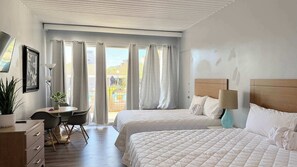 A hotel room with two beds, a desk, a chair, a lamp, and a view of the outdoors. - SJ1 Lovely studio with pool (Myrtle Beach)