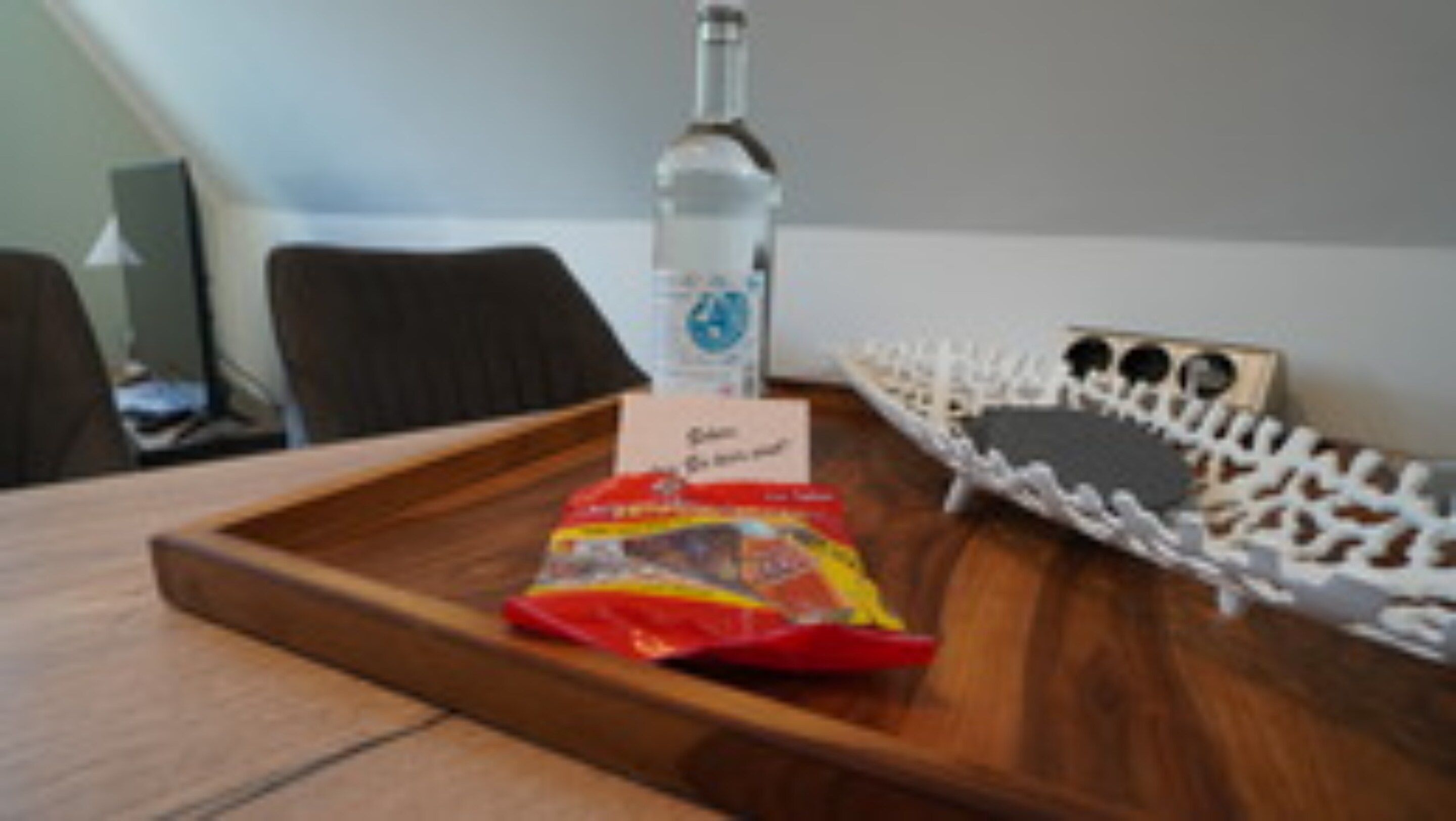 Un plateau contenant une bouteille, un paquet et une carte, posé sur une surface en bois.