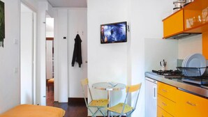 A compact kitchen with a dining area, a bed, and a TV on the wall. - Resort Village Rocchette Castiglione Della Pescaia (Castiglione della Pescaia)