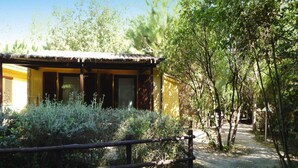 A rustic building with a thatched roof, surrounded by dense greenery and a wooden fence. - Resort Village Rocchette Castiglione Della Pescaia (Castiglione della Pescaia)