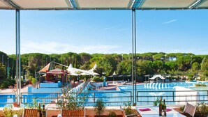 A rooftop pool area with tables and chairs, a view of the pool, and a covered seating area with umbrellas. - Resort Village Rocchette Castiglione Della Pescaia (Castiglione della Pescaia)