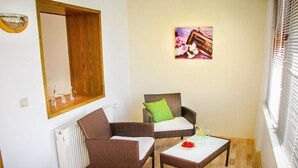 A small, cozy room with wicker furniture, a white radiator, and a picture on the wall. - Ferienwohnung in der Nahe vom Hexentanzplatz (Thale)