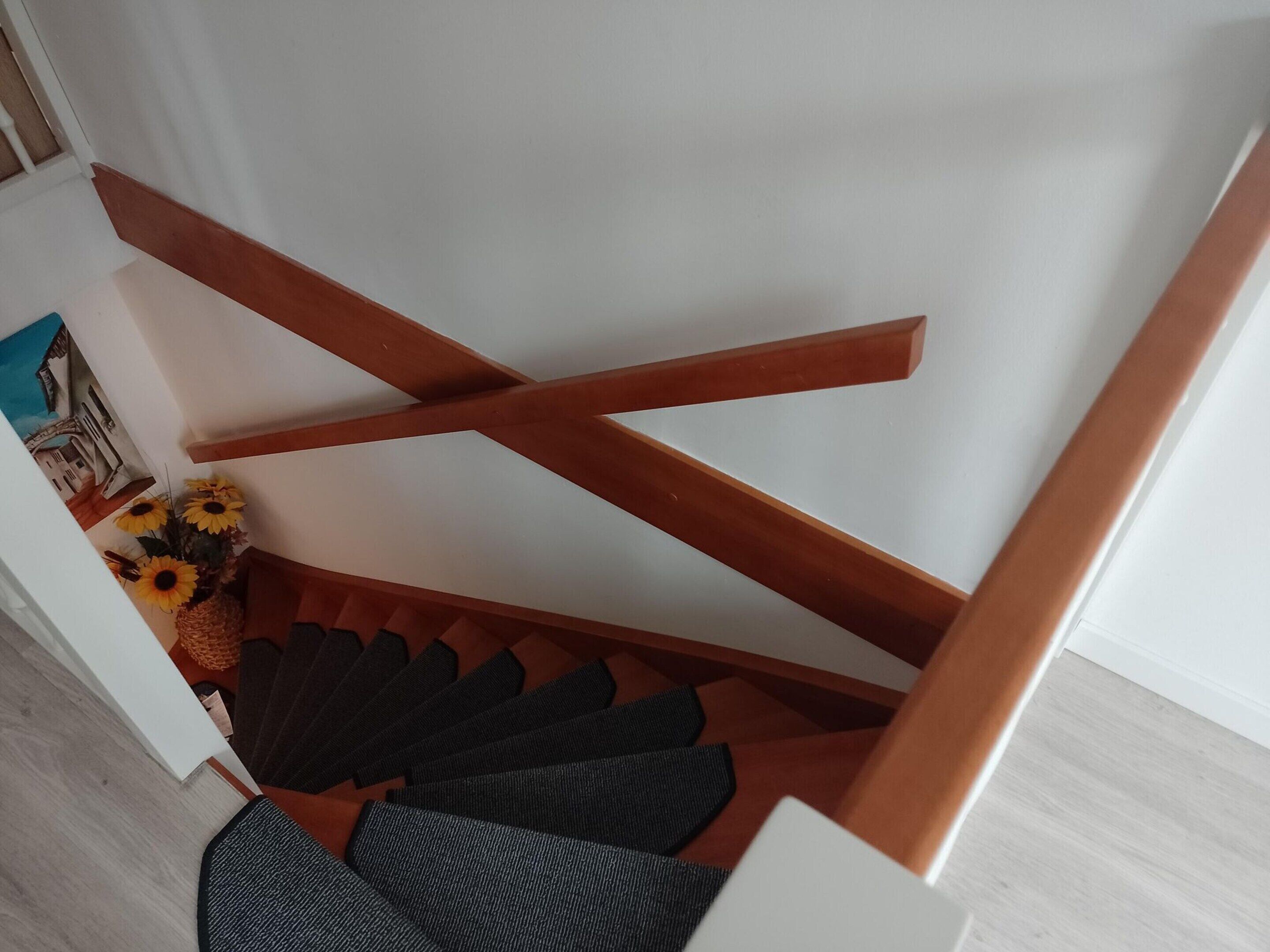 Eine Treppe mit hölzernen Geländern und einem Teppichpodest.