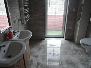 A modern bathroom with two sinks, a toilet, and a shower. - Holiday Home in Nowe Warpno Near Harbor (Nowe Warpno)