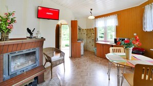 Ein gemütliches Wohnzimmer mit Kamin, einem an der Wand montierten Fernseher und einem Essbereich mit Tisch und Stühlen.