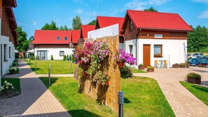 A row of red-roofed cottages with a reception area, surrounded by a well-maintained lawn and a paved walkway. - Comfortable Ground Floor Apartment, Summer Pool (Postomino)