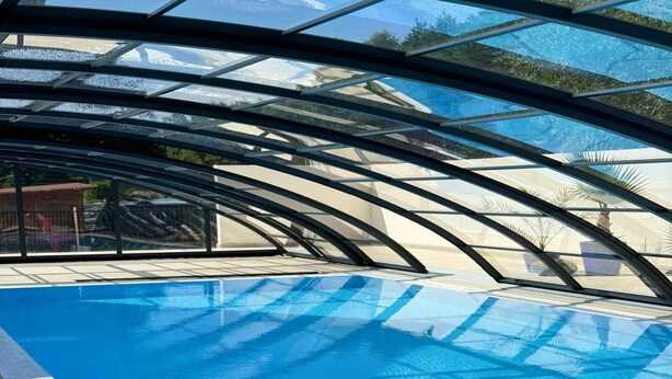 An indoor swimming pool with a glass ceiling and a view of the surrounding area. - Comfortable Ground Floor Apartment, Summer Pool (Postomino)