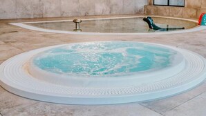 A hot tub with a circular design and a smaller rectangular hot tub in the background. - Air-conditioned Apartment, Indoor Pool, Sauna (Dziwnów)